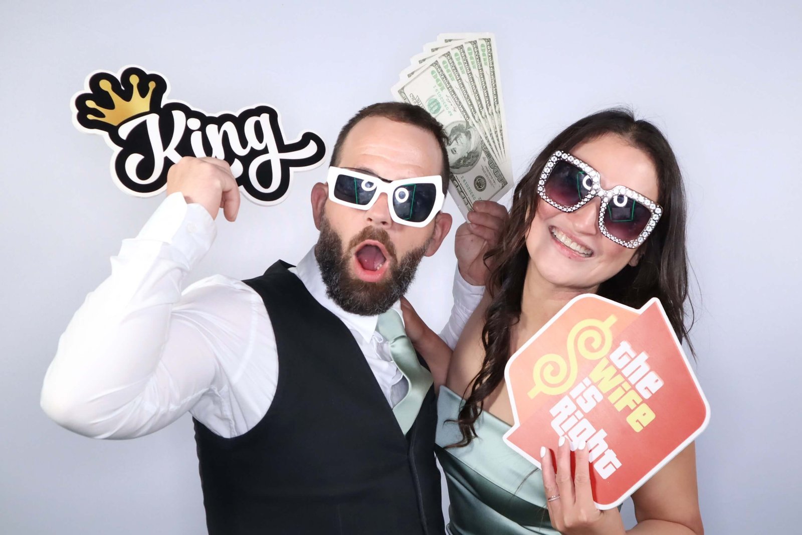 Bride and groom posing with fun props in a Peinc Studio booth